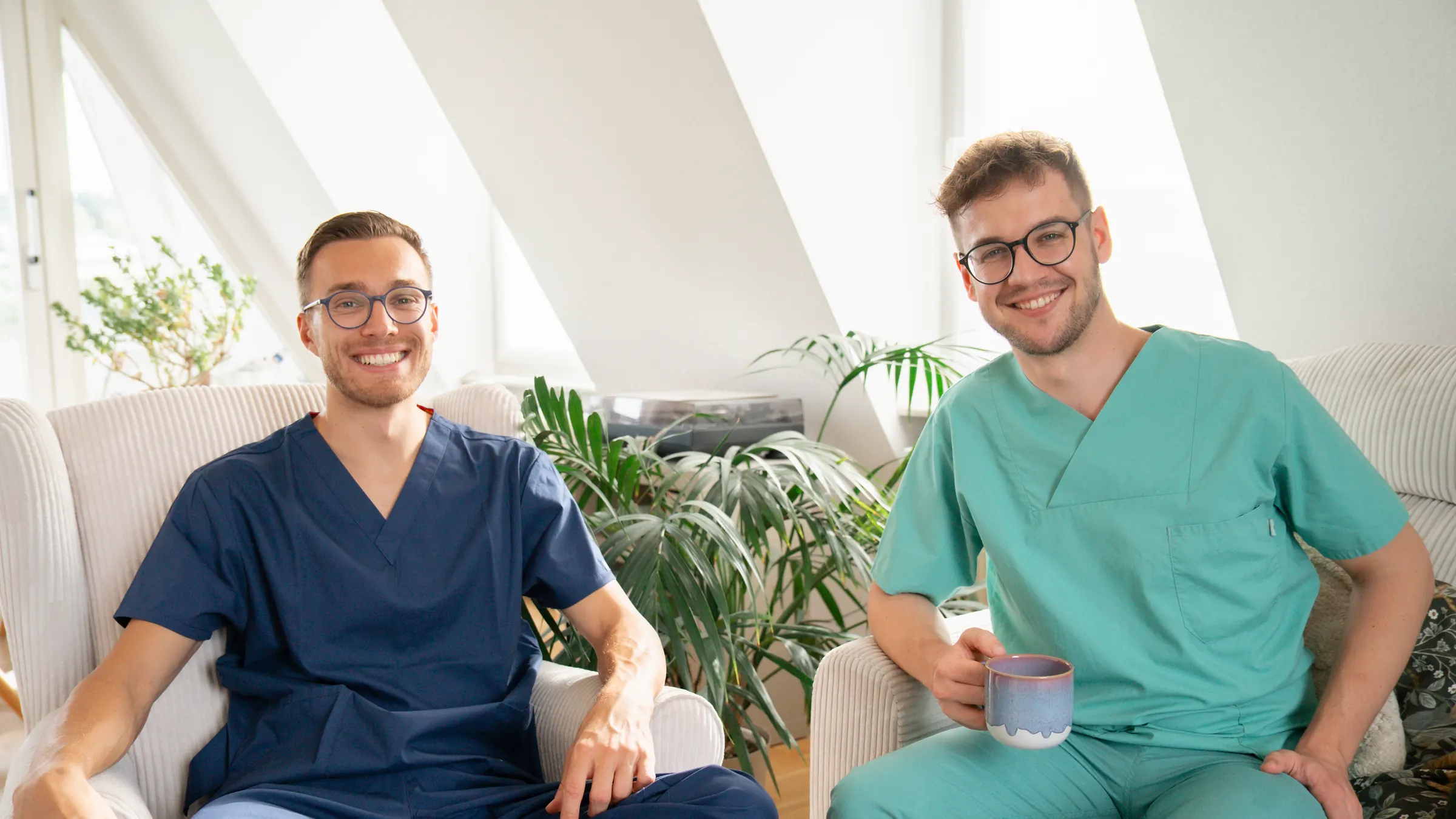 Moritz und Julian in OP-Kleidung, entspannt im Sessel